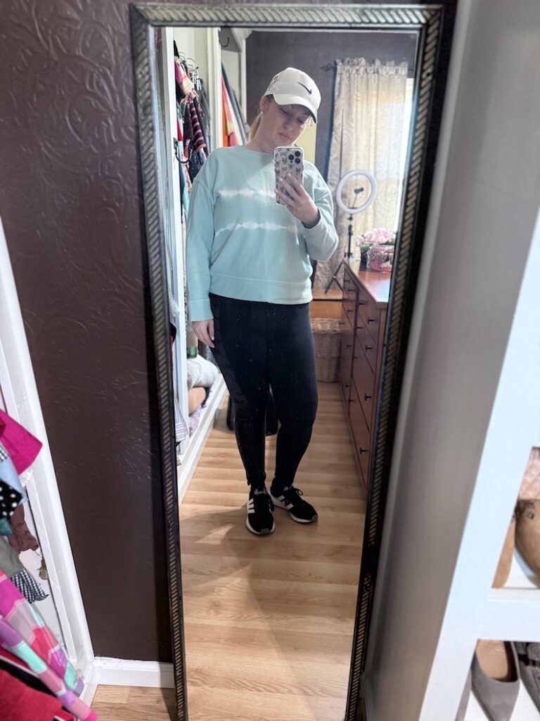 A woman standing in front of mirror taking a selfie wearing workout clothes. She is starting her health journey.