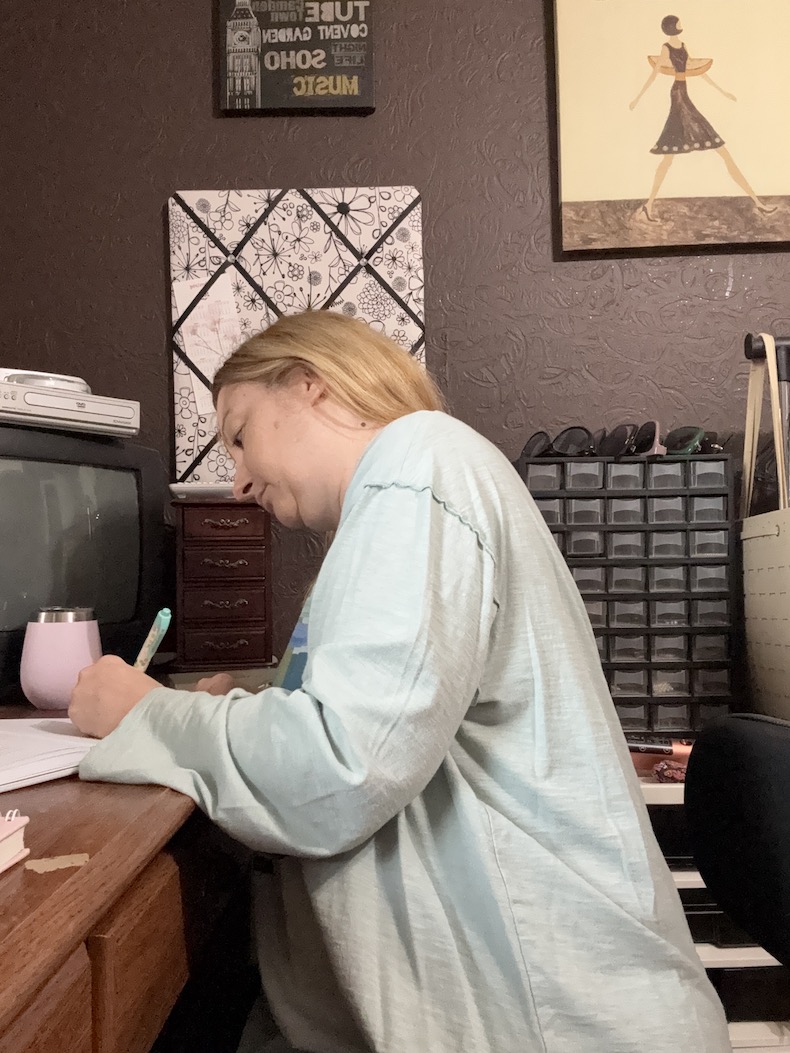 A woman sitting at her desk writing out her goals for the new year.